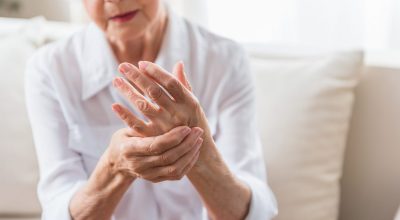 Arthritis. Close-up of hands of unhappy senior lady is feeling arm ache and expressing suffering. Copy space in the right side