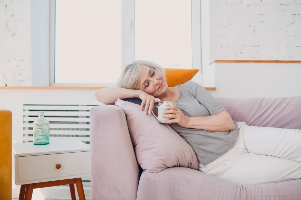 Vitale Seniorin entspannt im Wohnzimmer mit Tee