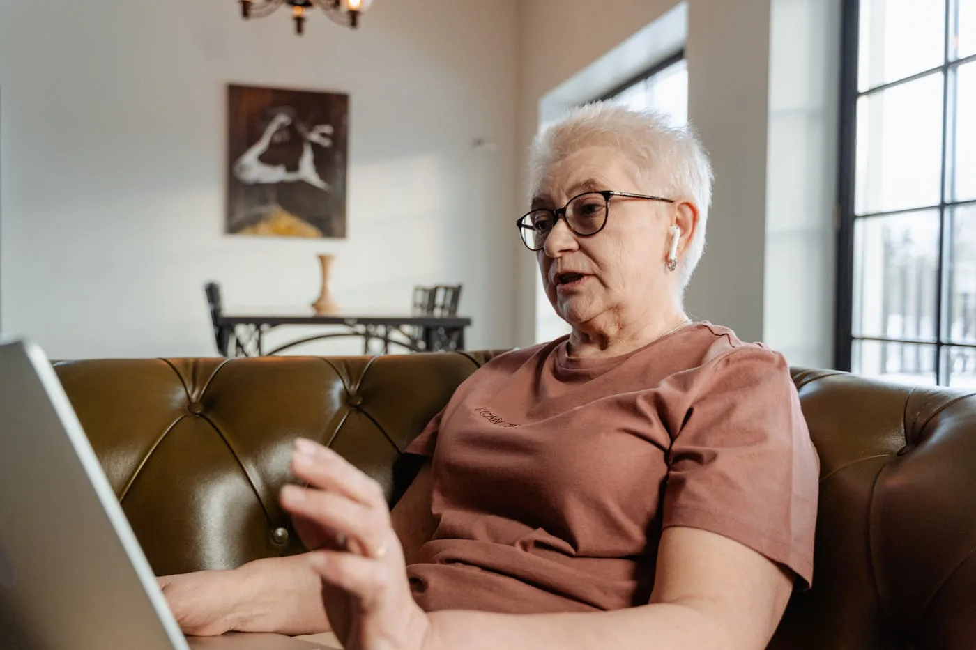 Seniorin verfolgt zu Hause am Laptop einen Online-Vortrag